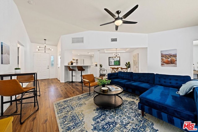 living room featuring ceiling fan with notable chandelier, lofted ceiling, and wood-type flooring