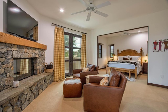 carpeted bedroom featuring french doors, a stone fireplace, and ceiling fan