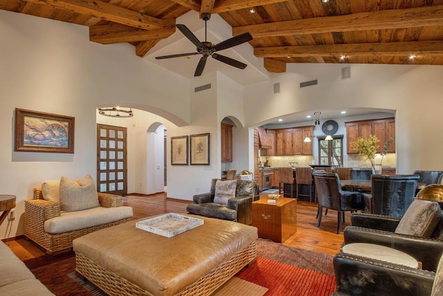 living room featuring beam ceiling, wooden ceiling, high vaulted ceiling, ceiling fan with notable chandelier, and hardwood / wood-style flooring