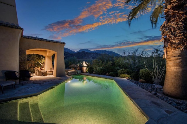 pool at dusk with a mountain view and a patio area