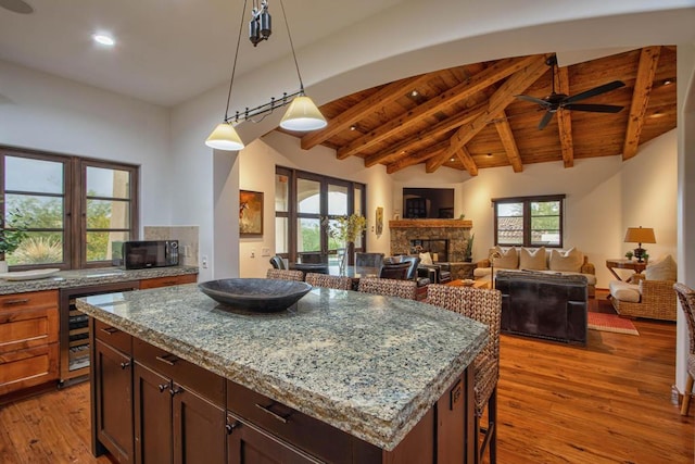 kitchen featuring light stone countertops, a kitchen island, light hardwood / wood-style flooring, a fireplace, and wine cooler