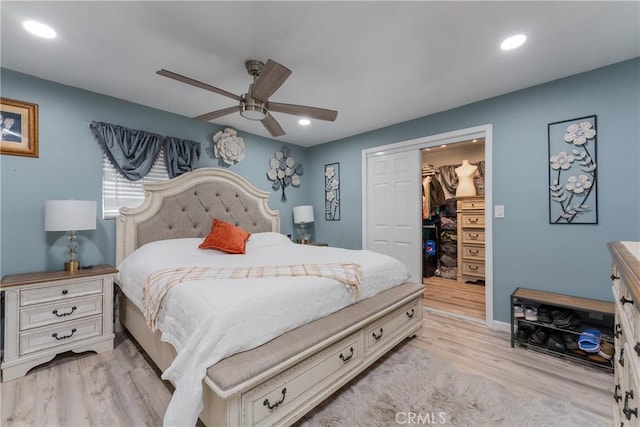 bedroom featuring a walk in closet, light hardwood / wood-style flooring, a closet, and ceiling fan