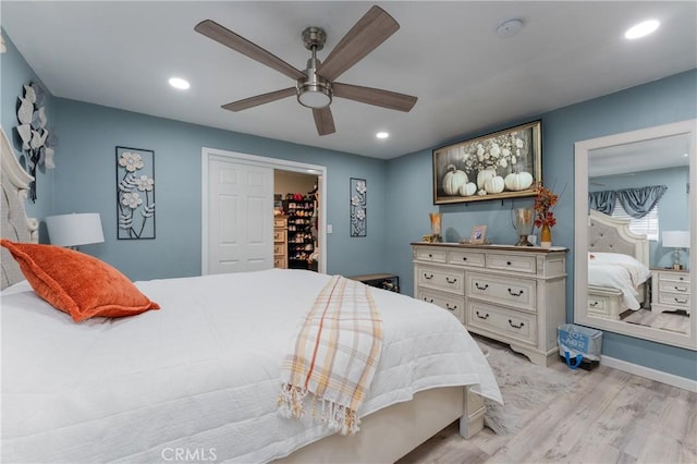 bedroom featuring a walk in closet, ceiling fan, a closet, and light hardwood / wood-style floors