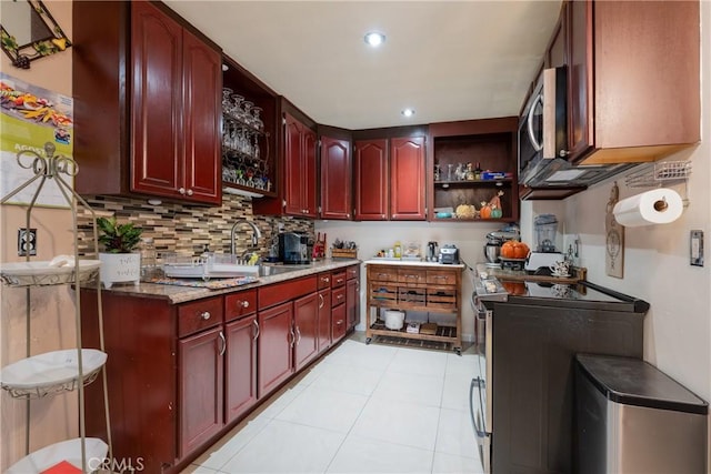 kitchen with light stone counters, light tile patterned flooring, sink, and backsplash