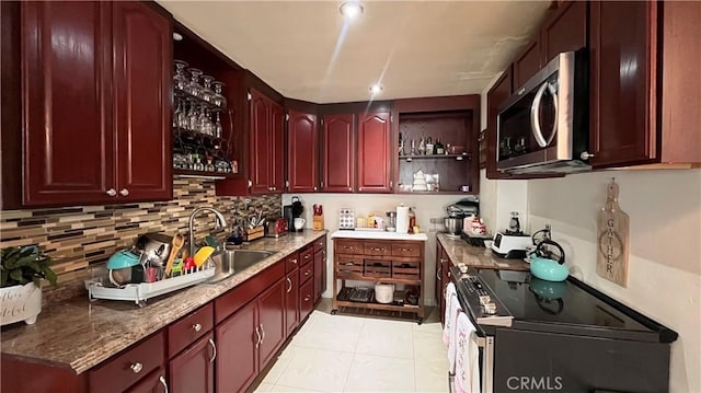 kitchen featuring light stone countertops, sink, decorative backsplash, light tile patterned flooring, and appliances with stainless steel finishes