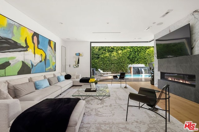 living room featuring a premium fireplace, light hardwood / wood-style flooring, and floor to ceiling windows