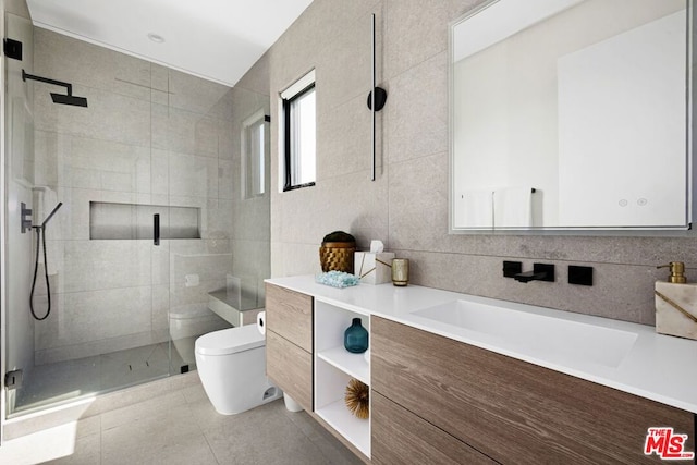 bathroom with vanity, toilet, tile walls, and a shower with door