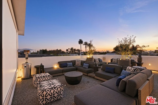 patio terrace at dusk featuring a baseboard radiator and an outdoor living space with a fire pit