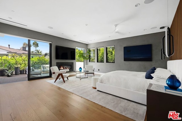 bedroom featuring access to exterior, multiple windows, and light wood-type flooring