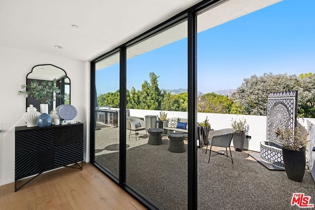 doorway with hardwood / wood-style floors and floor to ceiling windows