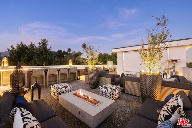 patio terrace at dusk featuring an outdoor living space with a fire pit