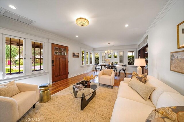 living room featuring a wealth of natural light, crown molding, and light wood-type flooring