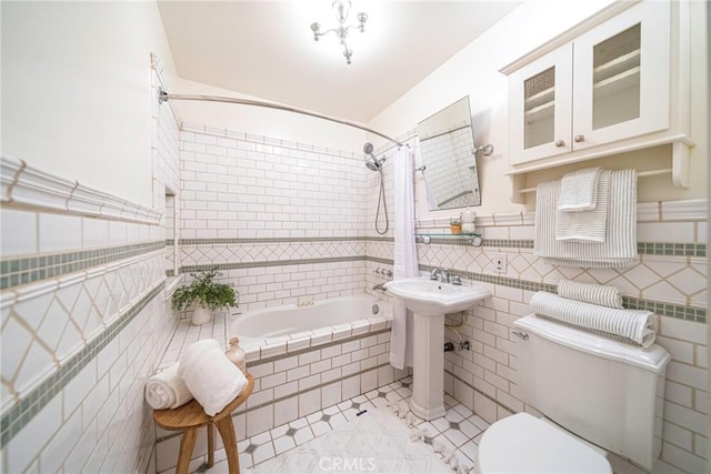 bathroom with tile walls, tile patterned floors, shower / bath combo with shower curtain, and toilet