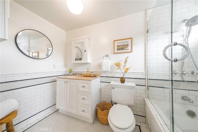 bathroom with vanity, toilet, tile walls, and a shower with shower door