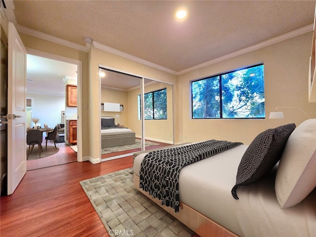 bedroom featuring hardwood / wood-style floors, ornamental molding, a textured ceiling, and a closet