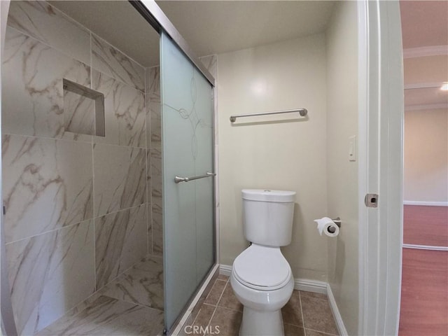 bathroom with tile patterned floors, toilet, and a shower with shower door