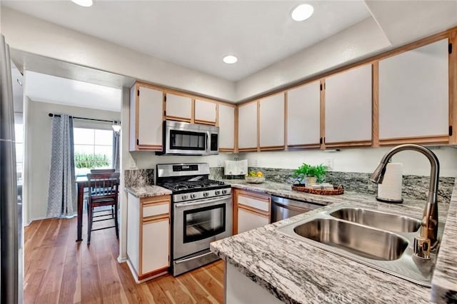 kitchen with white cabinets, stainless steel appliances, light hardwood / wood-style flooring, and sink