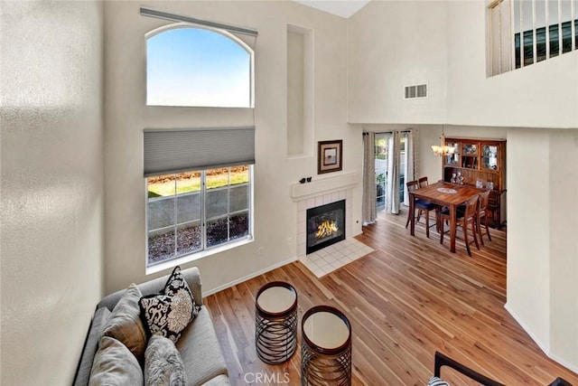 living room featuring a fireplace, hardwood / wood-style floors, a high ceiling, and a notable chandelier