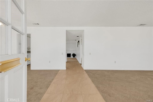 empty room featuring light colored carpet, light tile patterned floors, and visible vents