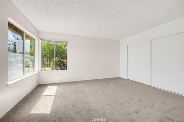 unfurnished bedroom featuring carpet floors, a textured ceiling, and a closet