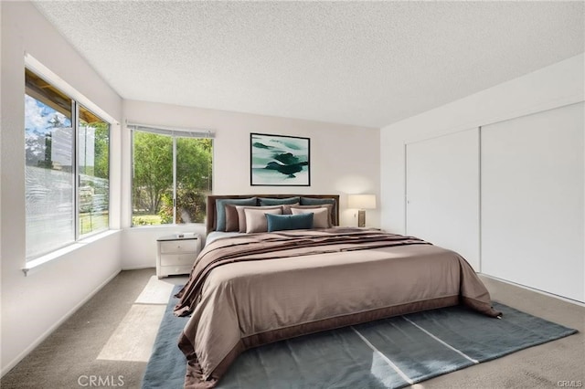 carpeted bedroom with a textured ceiling and a closet