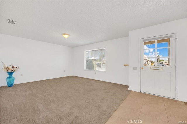 entryway with light carpet and a textured ceiling