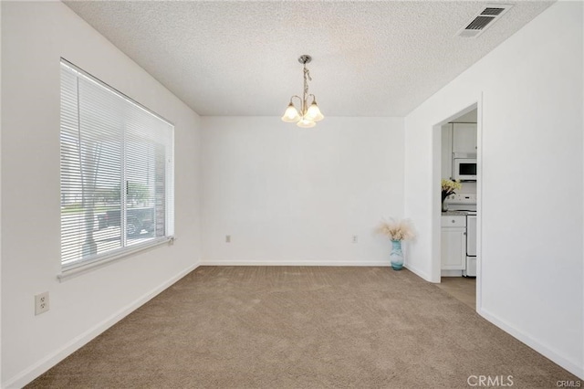 empty room featuring a textured ceiling, a chandelier, and light colored carpet