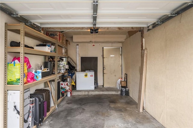 garage with a garage door opener and white refrigerator