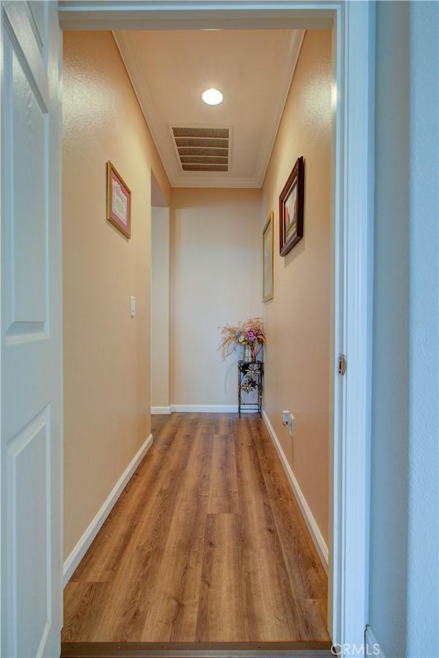 hall with ornamental molding and light hardwood / wood-style floors