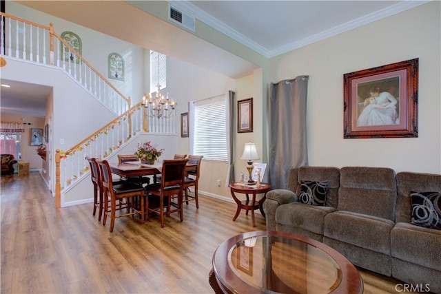 living room featuring crown molding, an inviting chandelier, and light wood-type flooring