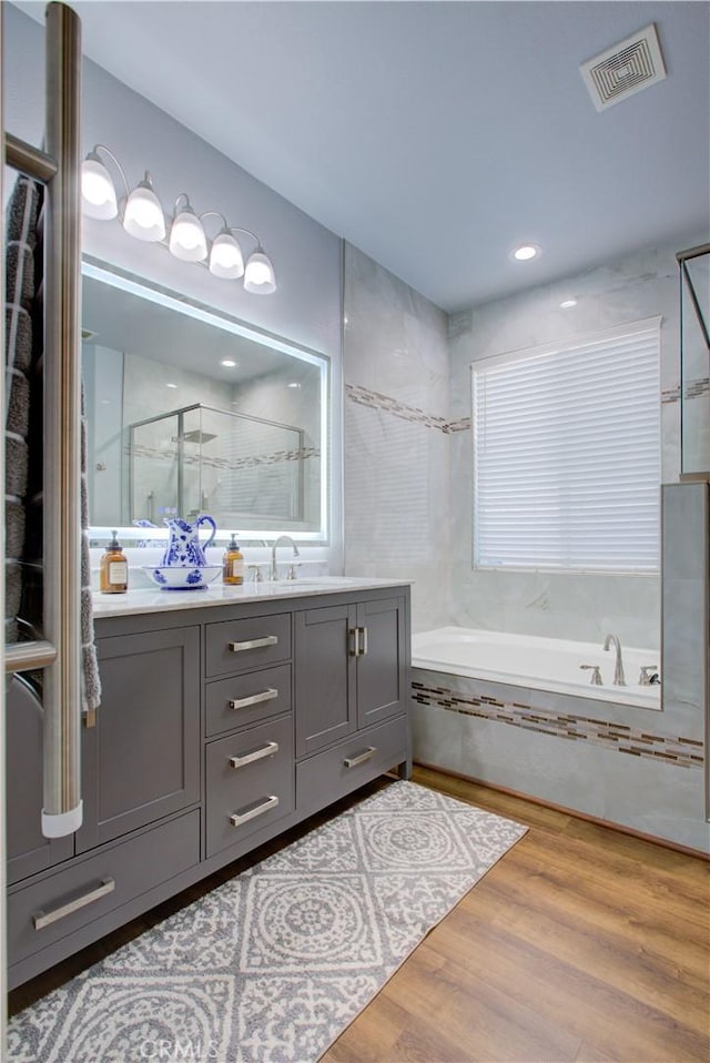 bathroom featuring hardwood / wood-style flooring, vanity, and shower with separate bathtub