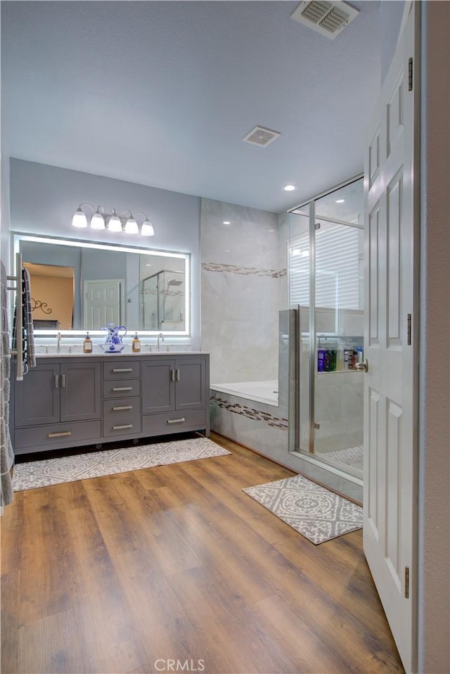 bathroom with hardwood / wood-style flooring, vanity, and shower with separate bathtub