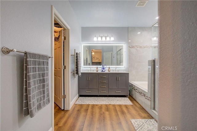 bathroom with hardwood / wood-style flooring, vanity, and separate shower and tub