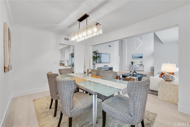 dining space with crown molding, light hardwood / wood-style floors, and an inviting chandelier