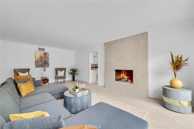 living room featuring a large fireplace, wood-type flooring, and crown molding