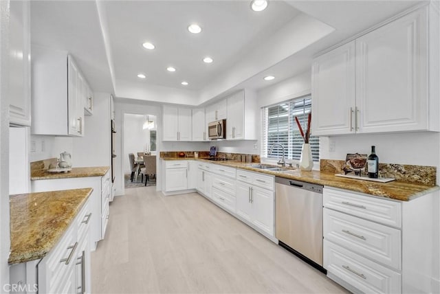 kitchen with stainless steel appliances, sink, light hardwood / wood-style flooring, stone counters, and white cabinetry