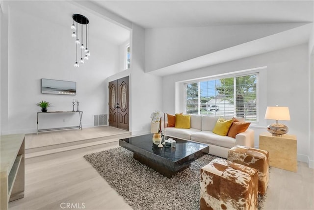 living room featuring light hardwood / wood-style floors and high vaulted ceiling