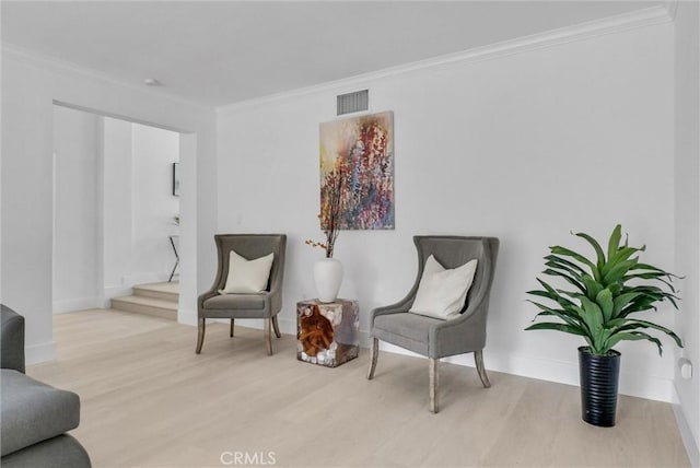 sitting room featuring crown molding and light hardwood / wood-style floors