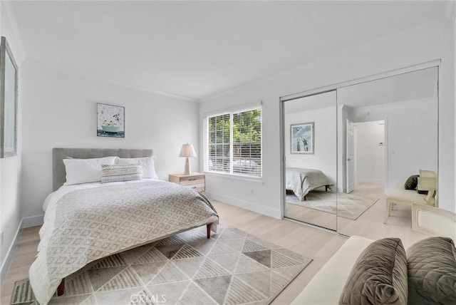 bedroom with light wood-type flooring, a closet, and ornamental molding