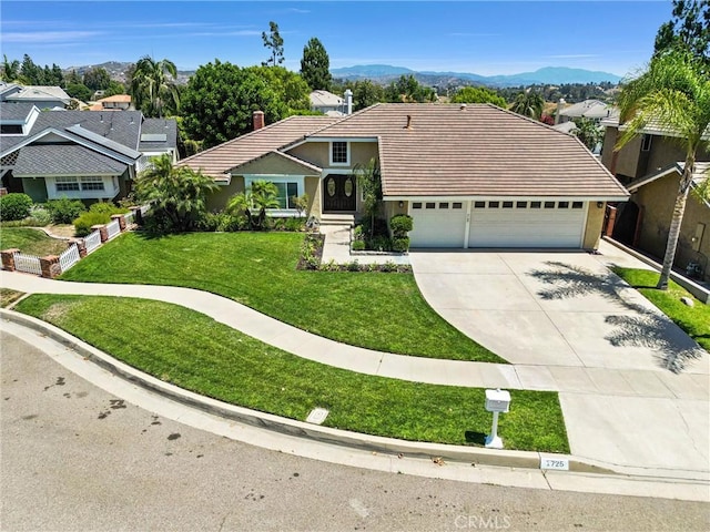 view of front of home featuring a mountain view, a front lawn, and a garage