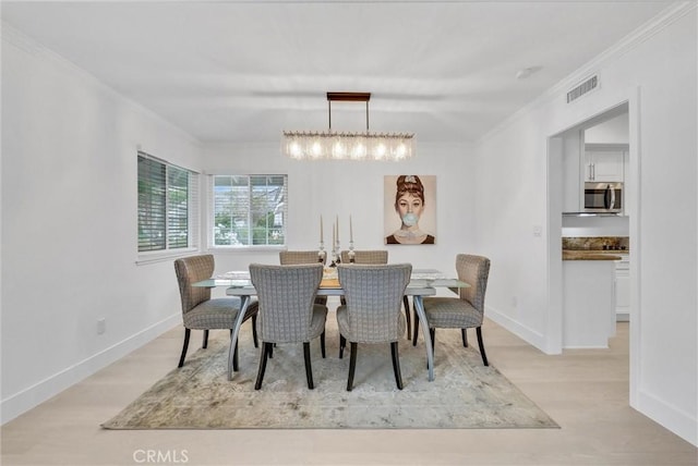 dining area with a chandelier, light hardwood / wood-style floors, and ornamental molding