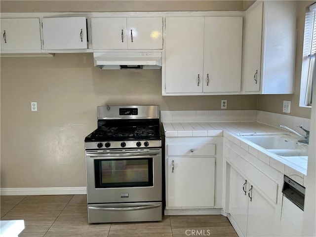 kitchen featuring tile countertops, sink, white dishwasher, stainless steel gas range, and white cabinets