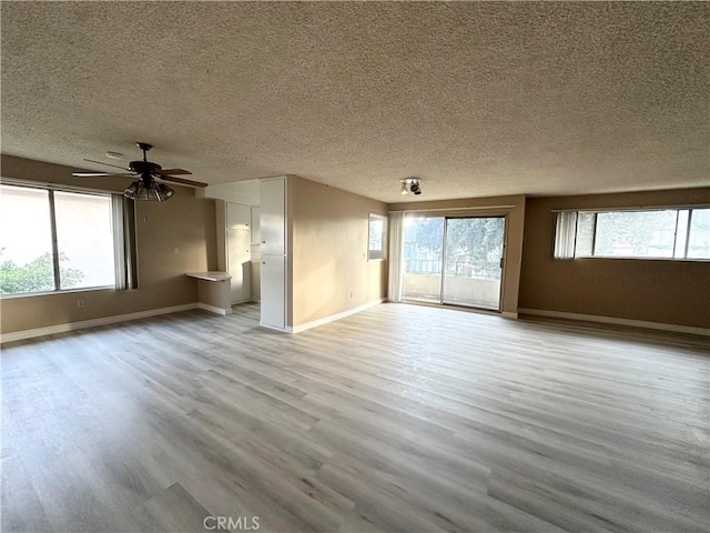 unfurnished living room with ceiling fan, a healthy amount of sunlight, a textured ceiling, and light hardwood / wood-style floors