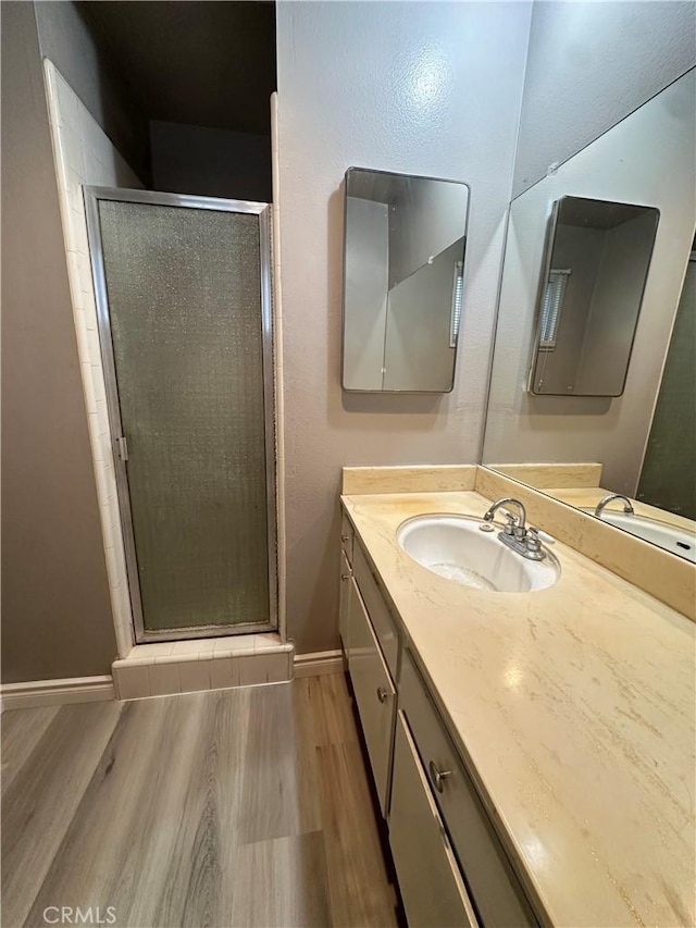 bathroom with a shower with shower door, vanity, and hardwood / wood-style flooring