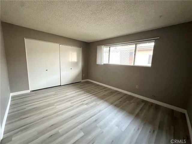 unfurnished bedroom with a closet, a textured ceiling, and light hardwood / wood-style flooring