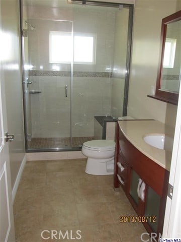 bathroom featuring vanity, an enclosed shower, and toilet