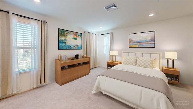 bedroom with light colored carpet and multiple windows