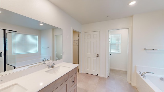 bathroom with tiled bath, vanity, and a healthy amount of sunlight