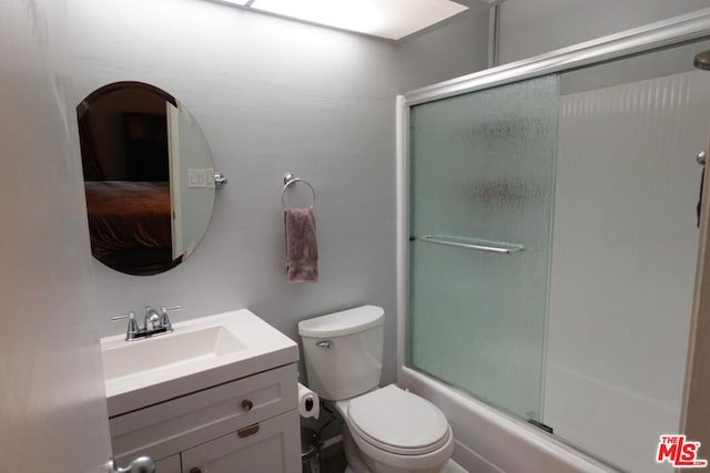 full bathroom with vanity, bath / shower combo with glass door, and toilet