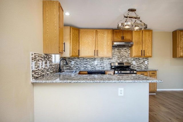 kitchen with gas range, light stone countertops, sink, dark hardwood / wood-style flooring, and kitchen peninsula